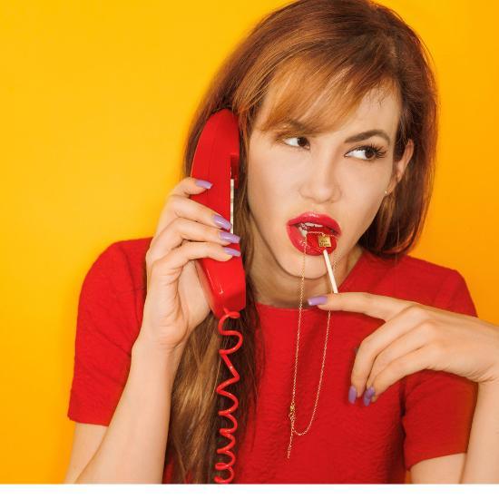 Woman in red shirt with a gold necklace stuck to a red lollipop.